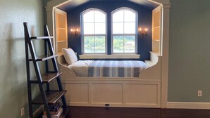 Ein Zimmer mit eingebautem Sitzplatz unter einem Erkerfenster, einer Leiter und einem Bücherregal.