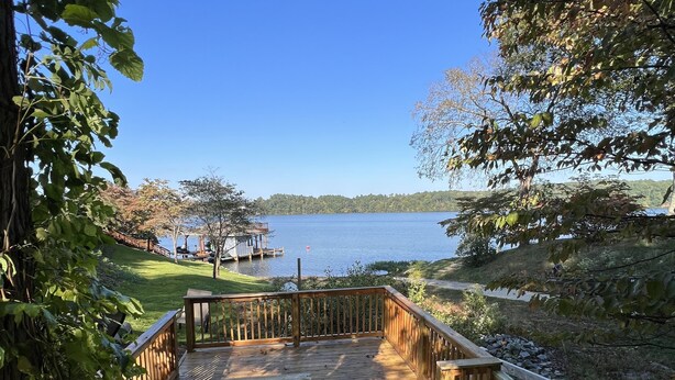 A wooden deck with a view of a lake and distant trees. - Charming home with lake views (Boydton)