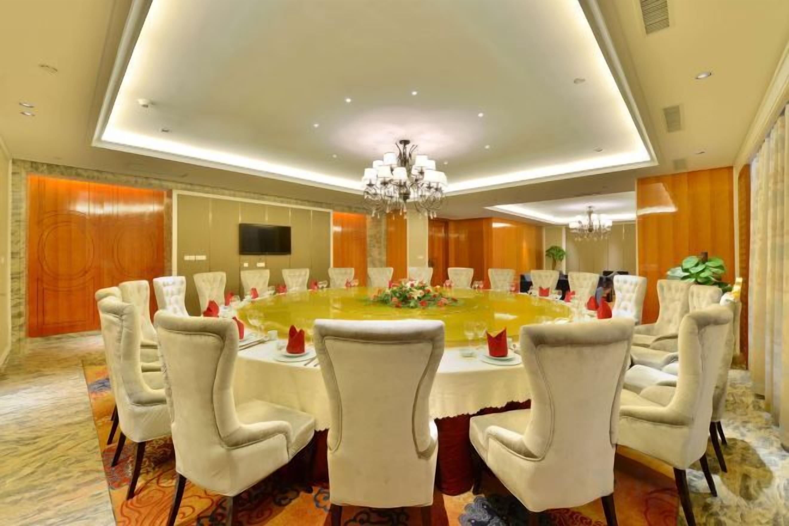 A conference room with a round table, white chairs, and a chandelier.