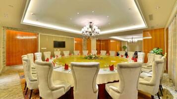A conference room with a round table, white chairs, and a chandelier.