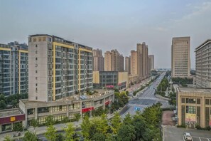 A cityscape with high-rise buildings, a wide road, and greenery. - Shenghe Regent Hotel (Changge)