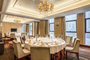 Une salle de conférence équipée d’une table ronde, de chaises et d’un lustre.