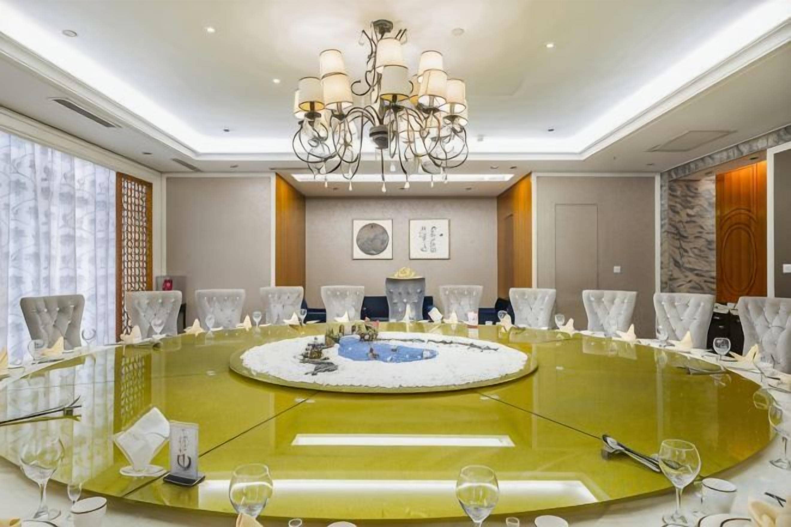 A conference room with a round table, chairs, a chandelier, and a decorative centerpiece.