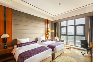 A hotel room with two beds, a large window, a desk, and a chair. - Shenghe Regent Hotel (Changge)