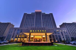 Un hotel con una entrada destacada, varios pisos y una fachada bien iluminada.