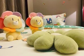 Two plush toys with flower-like appendages on a bed with a green and white patterned bedspread. - Shenghe Regent Hotel (Changge)