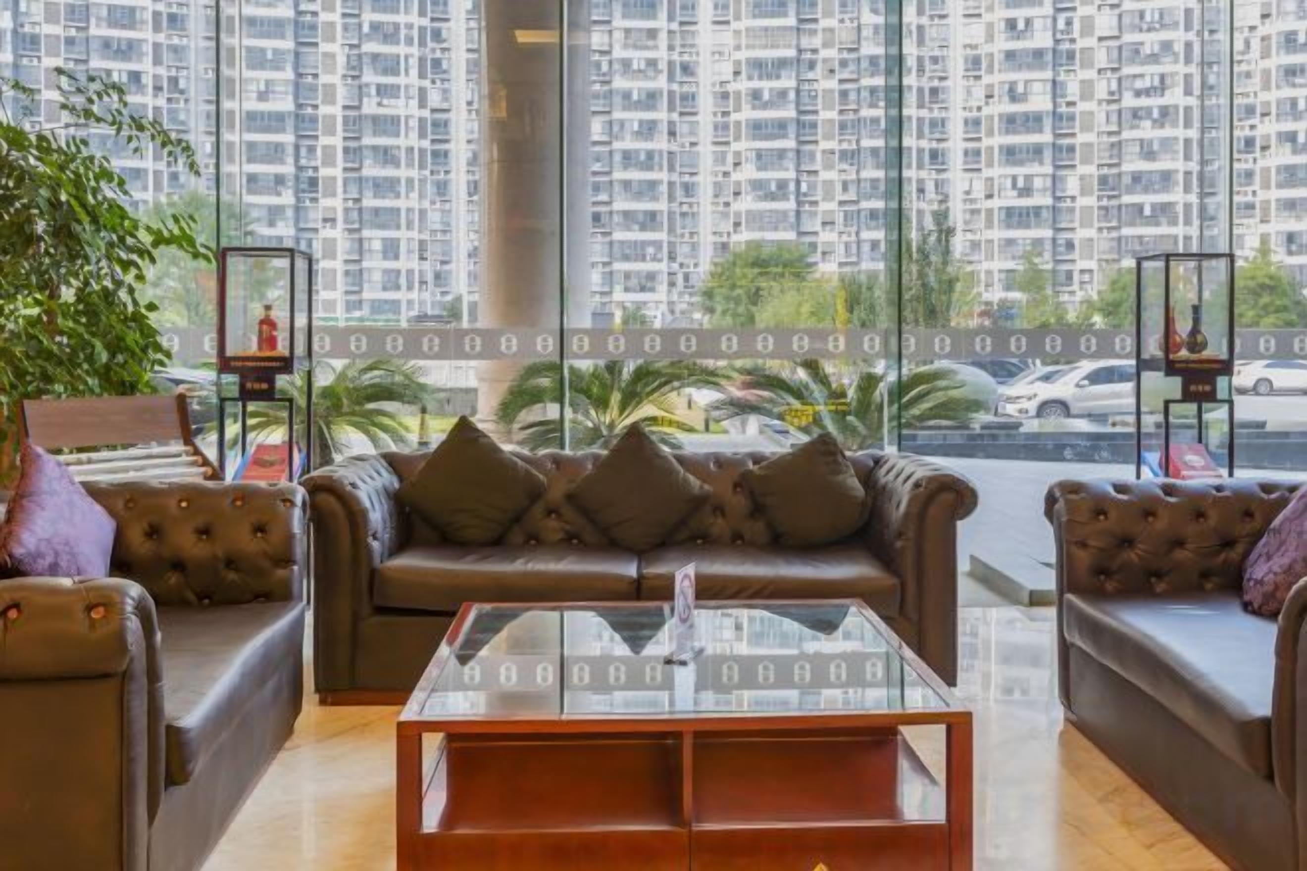 A living room with a sofa set, a glass coffee table, and a view of high-rise buildings.