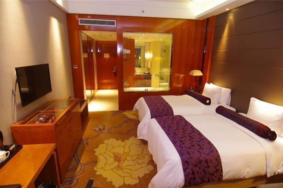 Quarto de hotel com duas camas, televisão, escrivaninha e espelho.