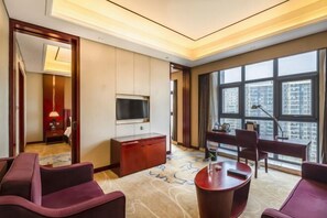 A hotel room with a large window, a flat-screen TV, a desk, and a seating area. - Shenghe Regent Hotel (Changge)