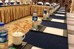 Une salle de conférence avec une longue table, des bouteilles d’eau et des plaques nominatives.