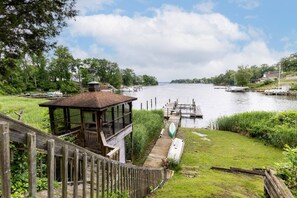 A wooden deck with a gazebo overlooking a river, docks, and boats.