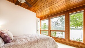 A bedroom with a large bed, wooden ceiling, and large windows overlooking a body of water. - Waterfront Home w Pool, Pier & Parking Mins to Annapolis (Arnold)