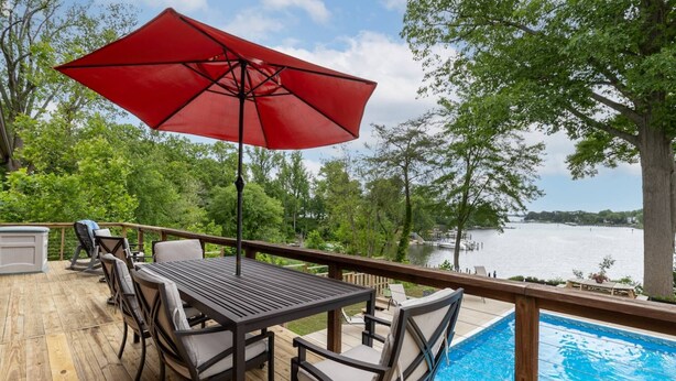 A wooden deck with a pool table, chairs, and a red umbrella. - Waterfront Home w Pool, Pier & Parking Mins to Annapolis (Arnold)