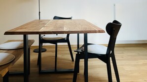 A modern dining area with a wooden table and black chairs, a floor lamp, and two wall clocks.