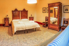 Une chambre d’hôtel avec un grand lit, une tête de lit en bois, une armoire, une petite table de chevet et un miroir.