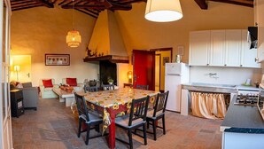 A cozy kitchen with a dining table, chairs, and a stove. - Casa Cassiodoro A: A characteristic age-old farm house surrounded by vineyards and olive groves, with Free WI-FI. (Castelfiorentino)