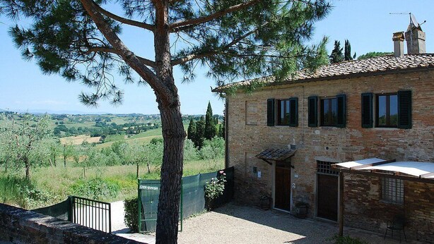 A stone building with a tiled roof, a large tree in front, and a view of a rural landscape. - Casa Cassiodoro A: A characteristic age-old farm house surrounded by vineyards and olive groves, with Free WI-FI. (Castelfiorentino)