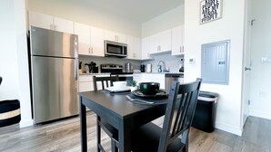 A modern kitchen with white cabinets, stainless steel appliances, and a dining table with chairs. - ★Black & White Themed| 1BD/1BA|Parking★ (Bound Brook)