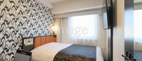 Habitación de hotel con cama, escritorio, silla, televisor y ventana con cortinas.
