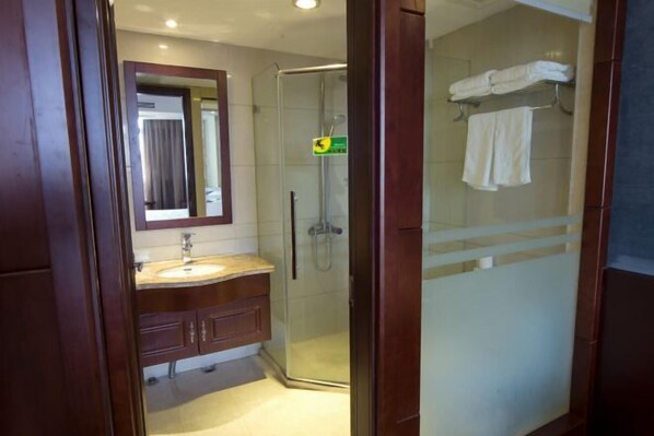 Une salle de bain avec une douche à parois de verre, un lavabo avec un miroir et un porte-serviettes avec des serviettes pliées.