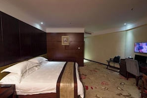 Une chambre d’hôtel avec un grand lit, une télévision et un bureau.