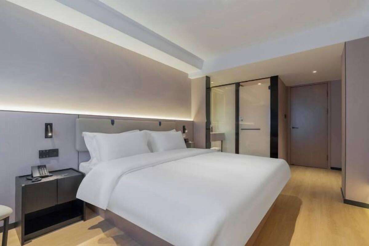 Een moderne hotelkamer met een groot bed, nachtkastjes en een inloopkast.