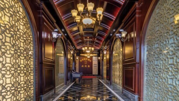 Un hall d’entrée luxueux, avec des murs richement décorés, des lustres et un sol en marbre poli.
