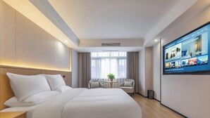 Une chambre d’hôtel avec un grand lit, un téléviseur fixé au mur, une petite table et deux chaises.