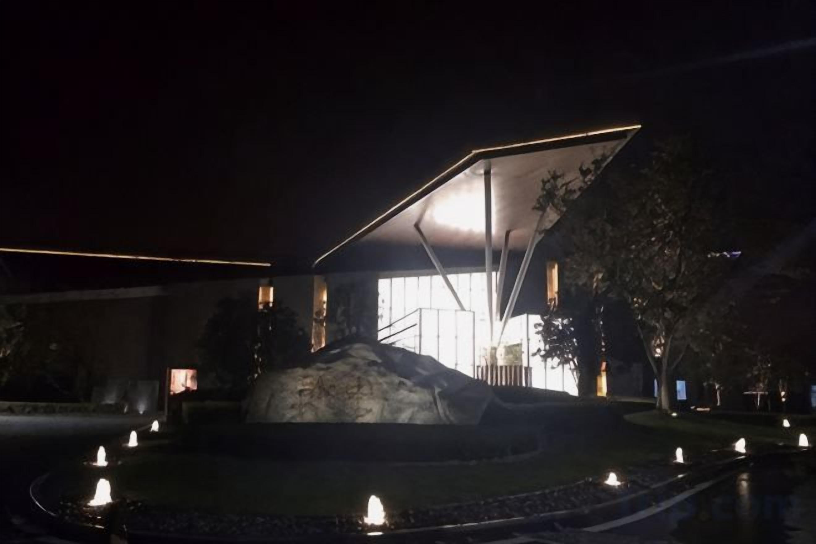 Un bâtiment moderne doté d’une architecture originale, avec une grande entrée illuminée et une cour intérieure agrémentée d’une fontaine.