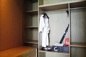 A walk-in closet with wooden shelves, a hanging rack, and a bench. - Arcadia Hotel (Jiangyin)