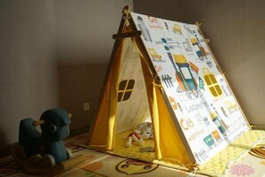 A tent with a train-themed interior, a toy train, and a plush toy on a play mat. - Arcadia Hotel (Jiangyin)