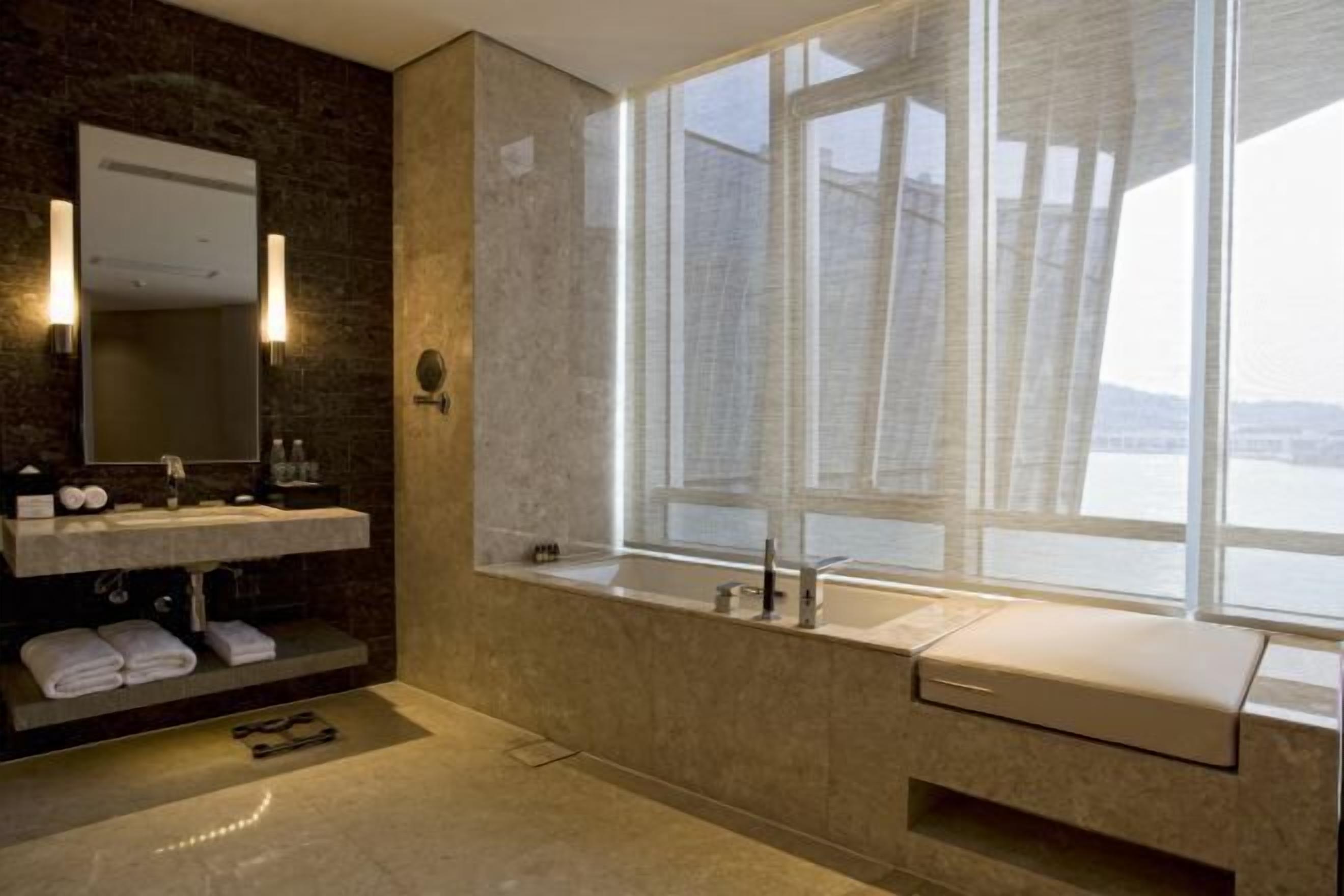 Een moderne badkamer met een groot raam, een ingebouwd wastafelmeubel en een spiegel.