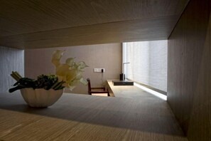 A minimalist room with a wooden floor, a large window, and a bowl of flowers on a table. - Arcadia Hotel (Jiangyin)