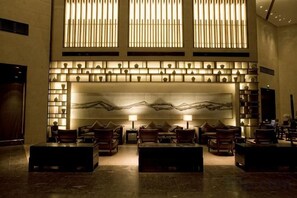 A lobby with a reception desk, seating area, and a large wall with a mountain painting. - Arcadia Hotel (Jiangyin)