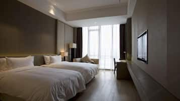 Een hotelkamer met twee bedden, een bureau, een stoel en een groot raam met gordijnen.