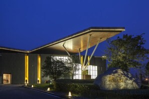 A modern building with a flat roof and a large rock in the foreground. - Arcadia Hotel (Jiangyin)