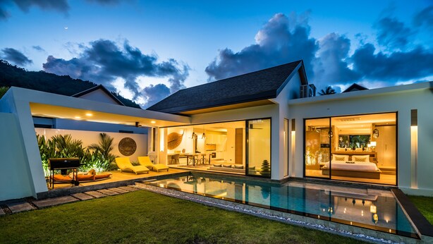 Ein modernes Haus mit Swimmingpool, einem gepflegten Rasen und einer großen Glasdoor, die zum Innenbereich führt.