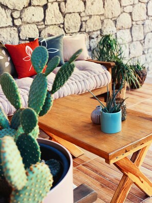 A cozy seating area with a stone wall, a wooden table, and various potted plants.