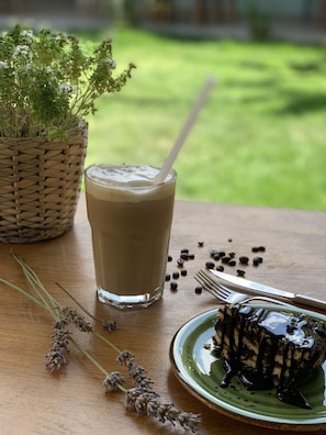 Un vaso de café helado sobre una mesa de madera, con un tenedor y un plato de postre de chocolate.
