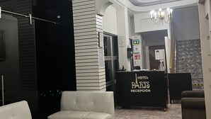 A hotel reception area with a chandelier, a reception desk, and seating arrangements. - Hotel Paris (San Juan de los Lagos)