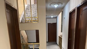 A hallway with a staircase, wooden doors, and a tiled floor. - Hotel Paris (San Juan de los Lagos)