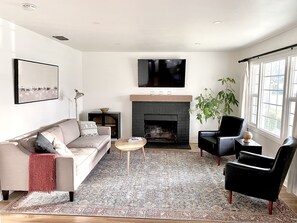 Ein modernes Wohnzimmer mit Kamin, einer Couch, einem Couchtisch und einem Fernseher.