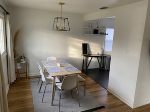 Un espace repas comprenant une table, des chaises, un tapis et un luminaire suspendu.