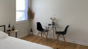 Un dormitorio con cama, mesita de noche, lámpara y ventana con persianas.