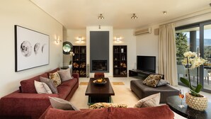 Ein modernes Wohnzimmer mit einer Sofagarnitur, einem Couchtisch, einem Kamin und einem Fernseher.