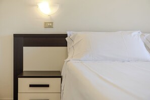 A hotel room with a bed, a nightstand, a wall-mounted light, and a power outlet. - Hotel Alla Torre (Garda)