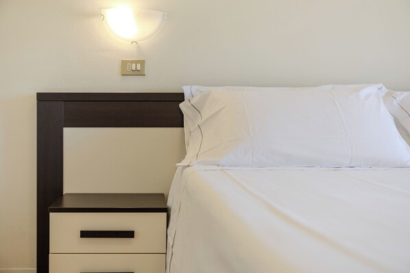 A hotel room with a bed, a nightstand, a wall-mounted light, and a power outlet. - Hotel Alla Torre (Garda)