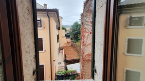 Un estrecho callejón entre edificios, con tejado de baldosas y un pequeño balcón con plantas en macetas.