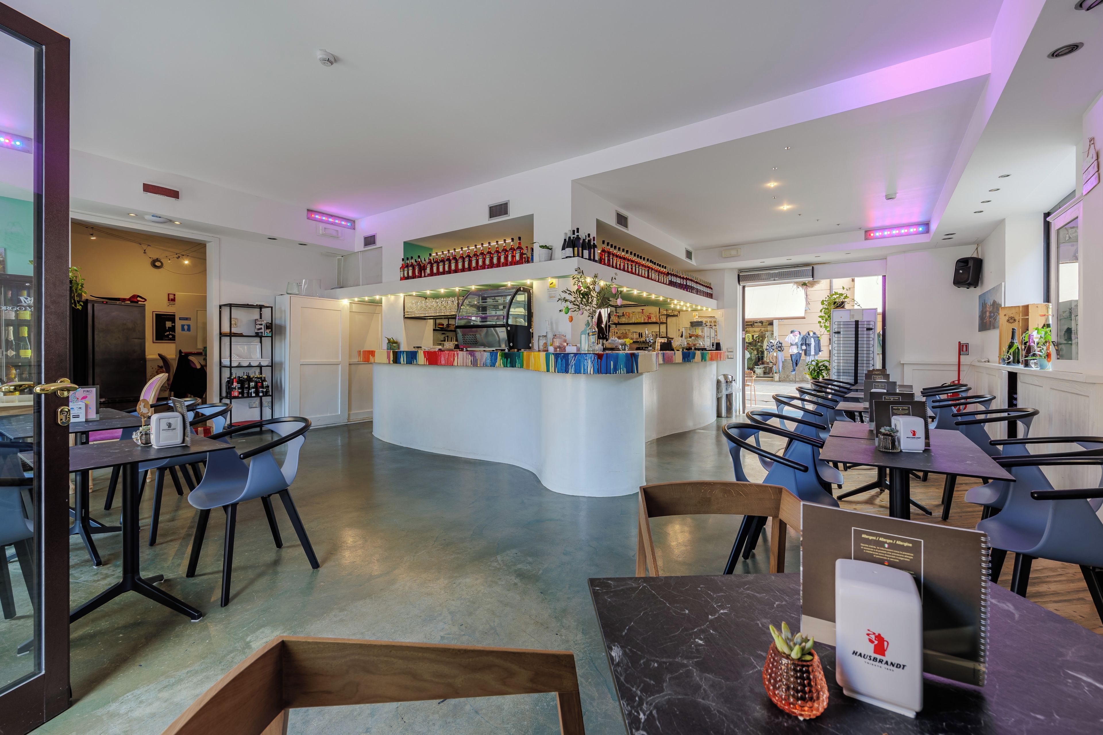 A modern restaurant with a central bar area, seating arrangements, and a variety of bottles on display.