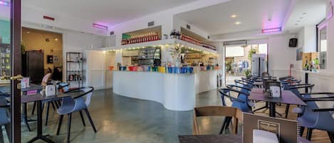 A modern restaurant with a central bar area, seating arrangements, and a variety of bottles on display.